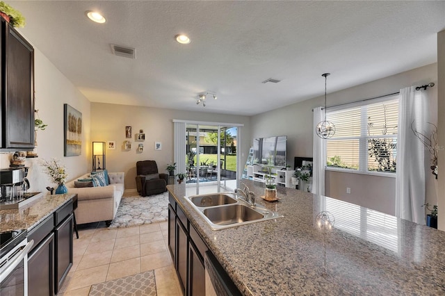 kitchen featuring a sink, visible vents, dark brown cabinetry, and light tile patterned floors