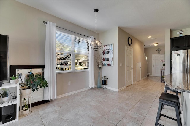 dining area with an inviting chandelier, light tile patterned floors, and baseboards