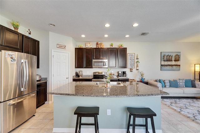 kitchen featuring a breakfast bar, open floor plan, visible vents, and stainless steel appliances