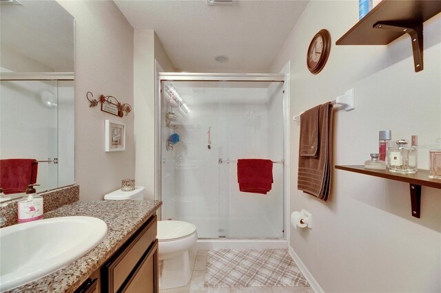 bathroom featuring tile patterned floors, a shower stall, vanity, and toilet