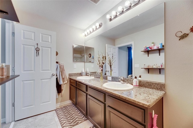 full bathroom with tile patterned flooring, double vanity, baseboards, and a sink