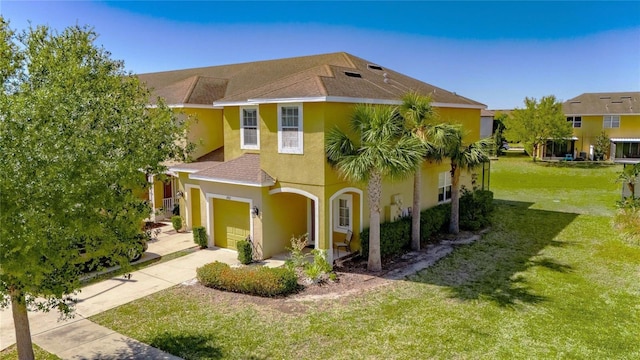 view of front facade with stucco siding, concrete driveway, a front yard, a shingled roof, and a garage