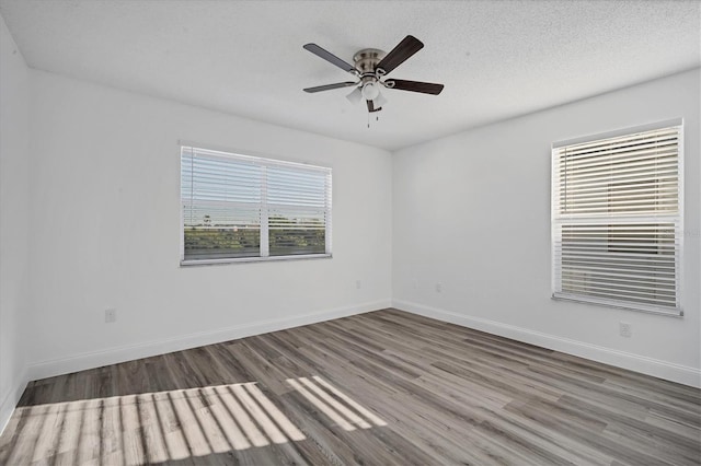 spare room featuring a ceiling fan, wood finished floors, baseboards, and a textured ceiling