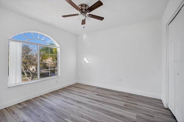 spare room featuring baseboards, a textured ceiling, wood finished floors, and a ceiling fan