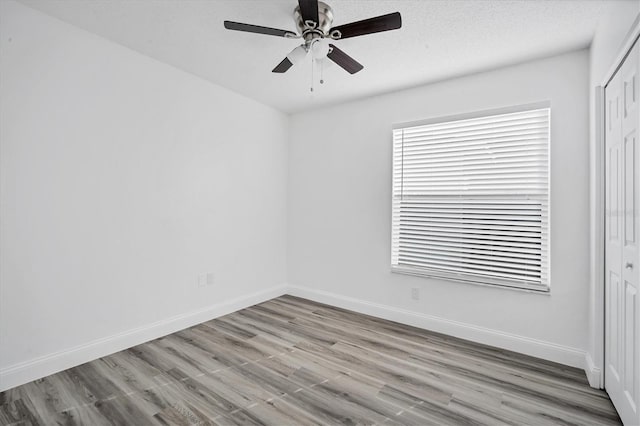 spare room featuring a ceiling fan, wood finished floors, baseboards, and a textured ceiling