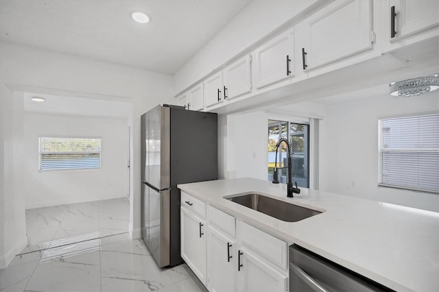 kitchen with a sink, marble finish floor, appliances with stainless steel finishes, and a wealth of natural light