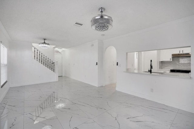 unfurnished living room with visible vents, marble finish floor, a sink, stairway, and arched walkways