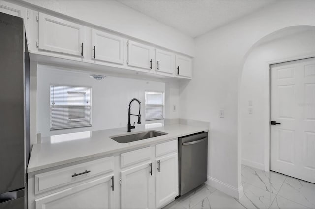 kitchen featuring light countertops, arched walkways, marble finish floor, stainless steel appliances, and a sink