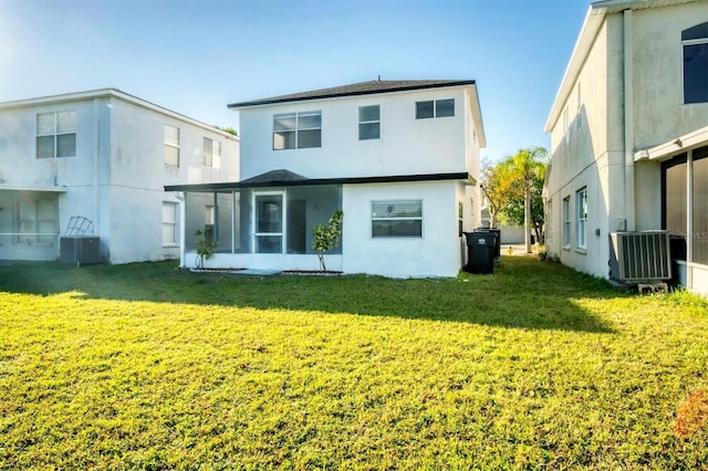 rear view of property with a yard, stucco siding, central AC, and a sunroom