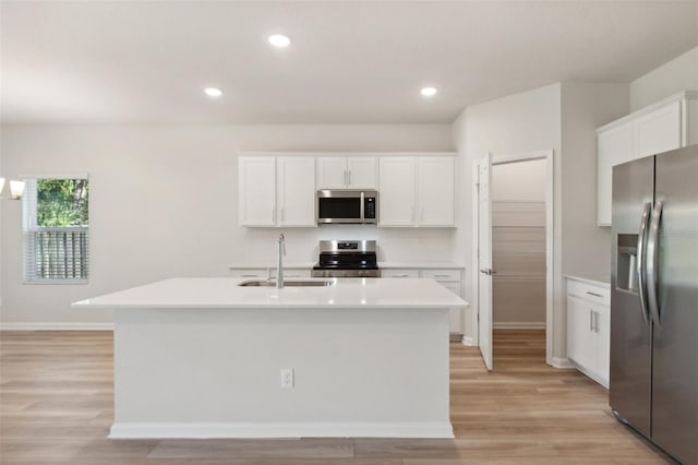 kitchen with light wood finished floors, a sink, light countertops, appliances with stainless steel finishes, and white cabinetry