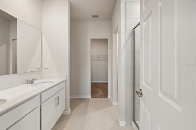 bathroom with a spacious closet, visible vents, a shower stall, double vanity, and a sink