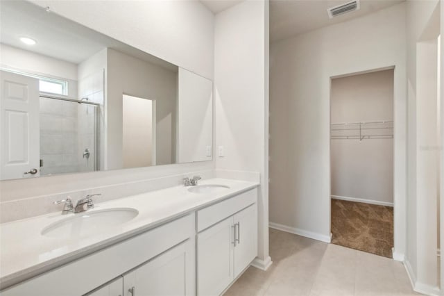 bathroom with a sink, visible vents, a spacious closet, and a shower stall