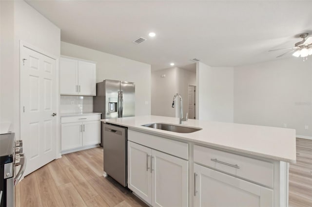 kitchen with light countertops, light wood-style floors, white cabinets, stainless steel appliances, and a sink