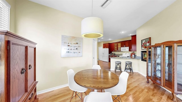 dining area featuring light wood-style flooring, visible vents, and baseboards