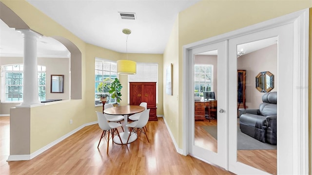 dining room with visible vents, baseboards, decorative columns, and light wood finished floors