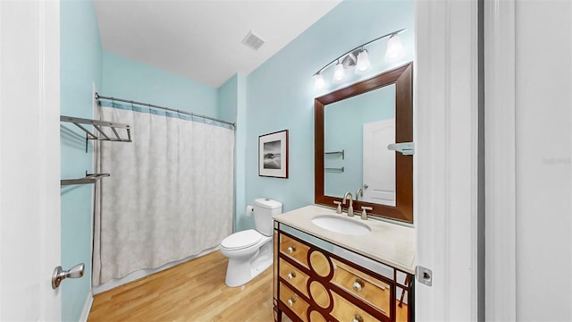 full bathroom with vanity, a shower with shower curtain, wood finished floors, visible vents, and toilet