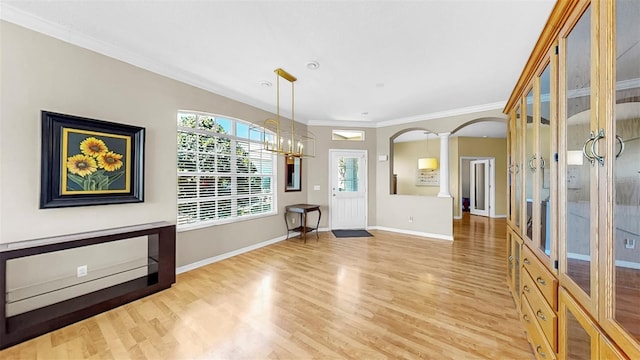 unfurnished dining area featuring light wood-type flooring, decorative columns, arched walkways, and crown molding