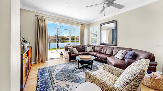 living area with baseboards, ceiling fan, ornamental molding, light wood-style floors, and a water view