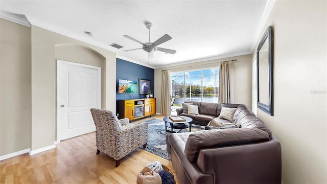 living room with crown molding, a ceiling fan, visible vents, and light wood-type flooring