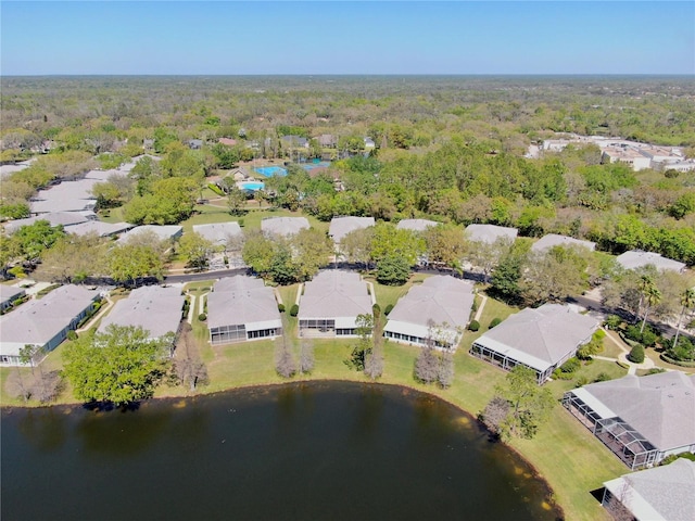 drone / aerial view with a view of trees, a water view, and a residential view