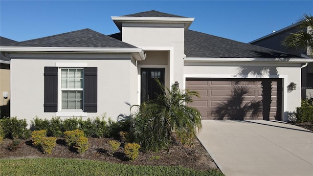 view of front of house with stucco siding, an attached garage, a shingled roof, and driveway