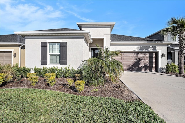 prairie-style home featuring a shingled roof, concrete driveway, a garage, and stucco siding