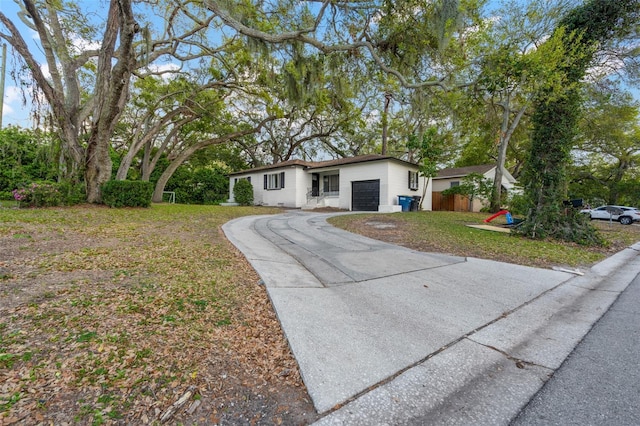 ranch-style house featuring a front yard, concrete driveway, and an attached garage