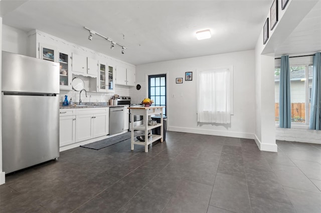 kitchen with decorative backsplash, a sink, appliances with stainless steel finishes, white cabinets, and glass insert cabinets