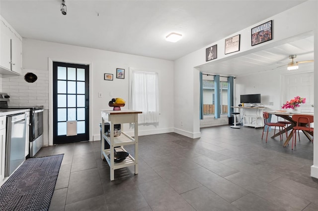 kitchen featuring baseboards, open floor plan, dishwasher, white cabinetry, and range