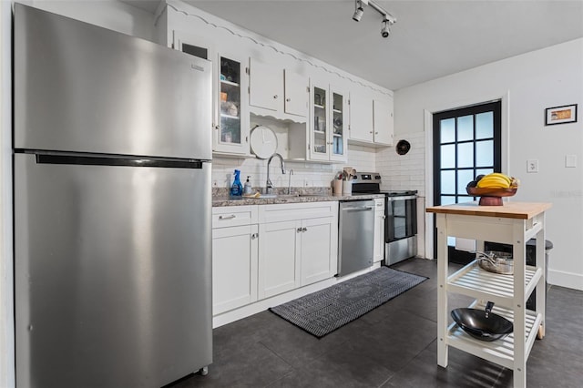 kitchen with a sink, stainless steel appliances, white cabinets, glass insert cabinets, and tasteful backsplash