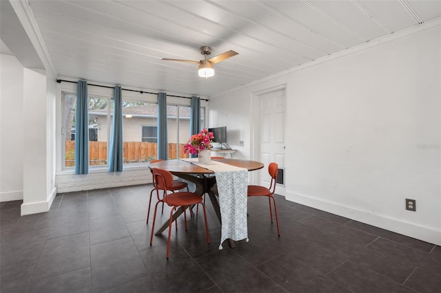 dining space featuring dark tile patterned floors, a ceiling fan, baseboards, and ornamental molding