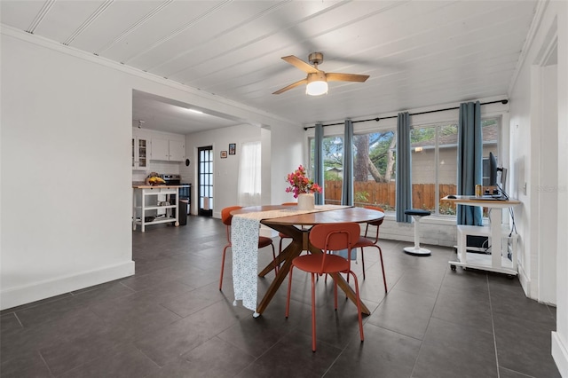 dining space with crown molding, baseboards, and ceiling fan