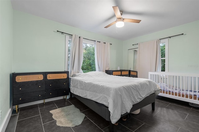 bedroom with baseboards, dark tile patterned floors, and a ceiling fan