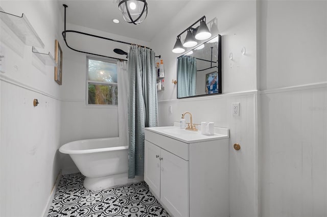 bathroom with tile patterned floors, a soaking tub, wainscoting, and vanity