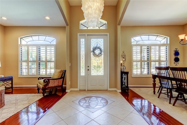 tiled entrance foyer with arched walkways, a chandelier, recessed lighting, and baseboards