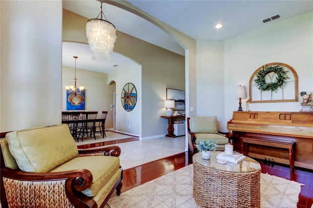 living area with visible vents, baseboards, wood finished floors, arched walkways, and a notable chandelier