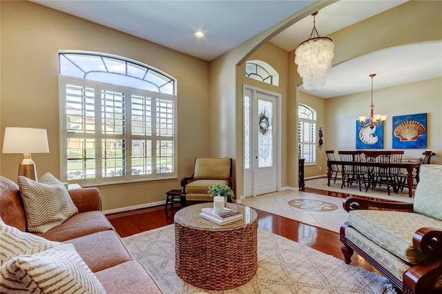 living area with an inviting chandelier, wood finished floors, baseboards, and arched walkways