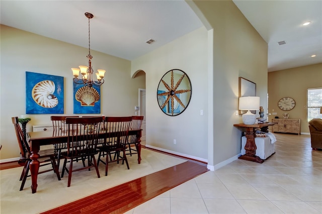 tiled dining room featuring visible vents, arched walkways, a notable chandelier, and baseboards