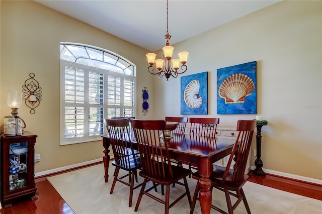 dining space with baseboards, an inviting chandelier, and wood finished floors