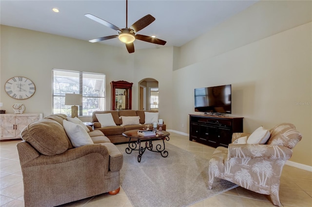 living area with light tile patterned floors, arched walkways, and a ceiling fan