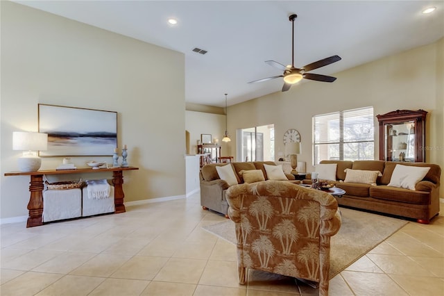 living room with light tile patterned floors, visible vents, baseboards, and a ceiling fan