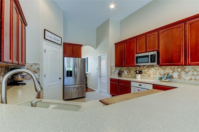 kitchen with a sink, backsplash, appliances with stainless steel finishes, light countertops, and dark brown cabinets