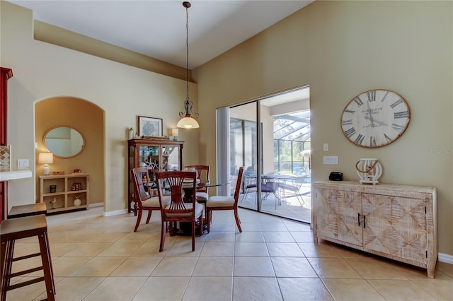 dining space with light tile patterned flooring, arched walkways, and baseboards