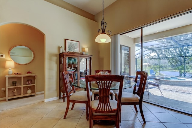 dining area with baseboards, light tile patterned floors, a towering ceiling, a sunroom, and arched walkways