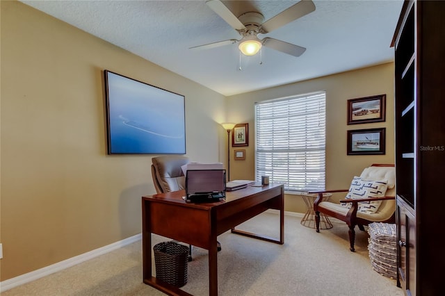 office area with baseboards, light carpet, a textured ceiling, and ceiling fan