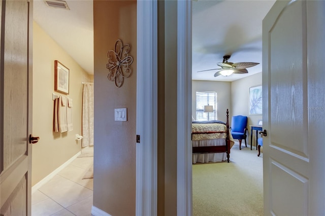 hallway featuring light tile patterned floors, visible vents, and baseboards