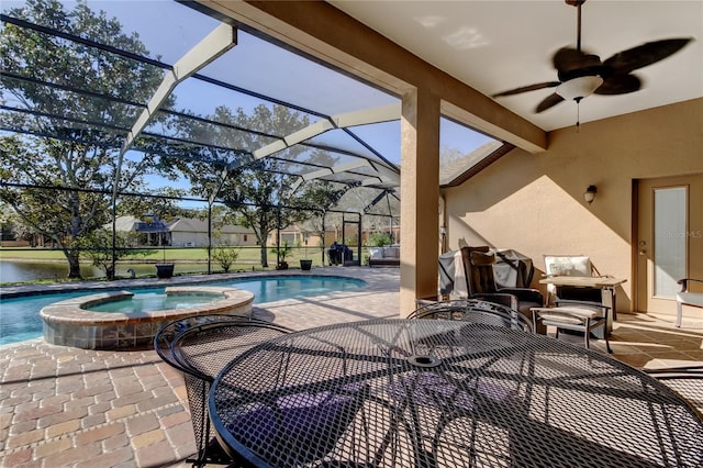 view of pool featuring glass enclosure, a patio area, a pool with connected hot tub, and ceiling fan