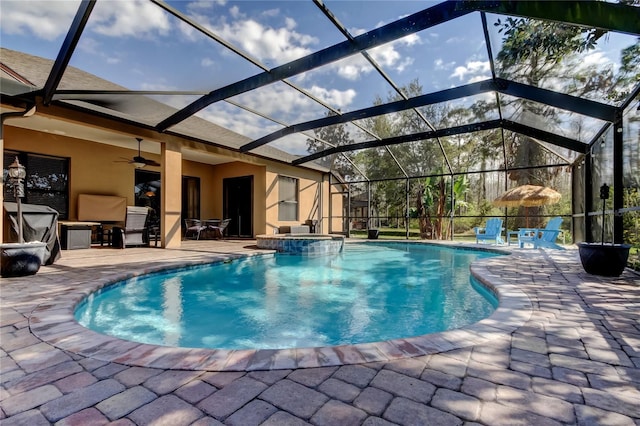 view of swimming pool with glass enclosure, a patio, a ceiling fan, and a pool with connected hot tub