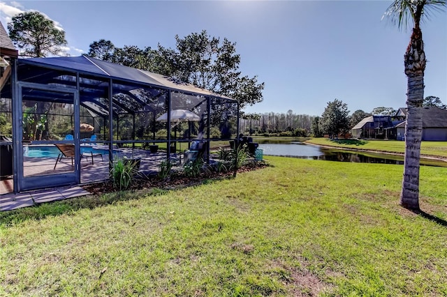 view of yard with glass enclosure, an outdoor pool, and a water view