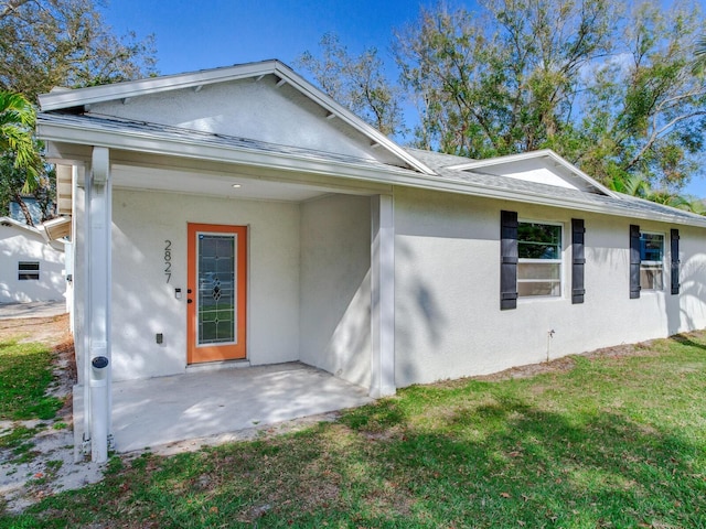 view of front of property featuring stucco siding, a patio, and a front yard